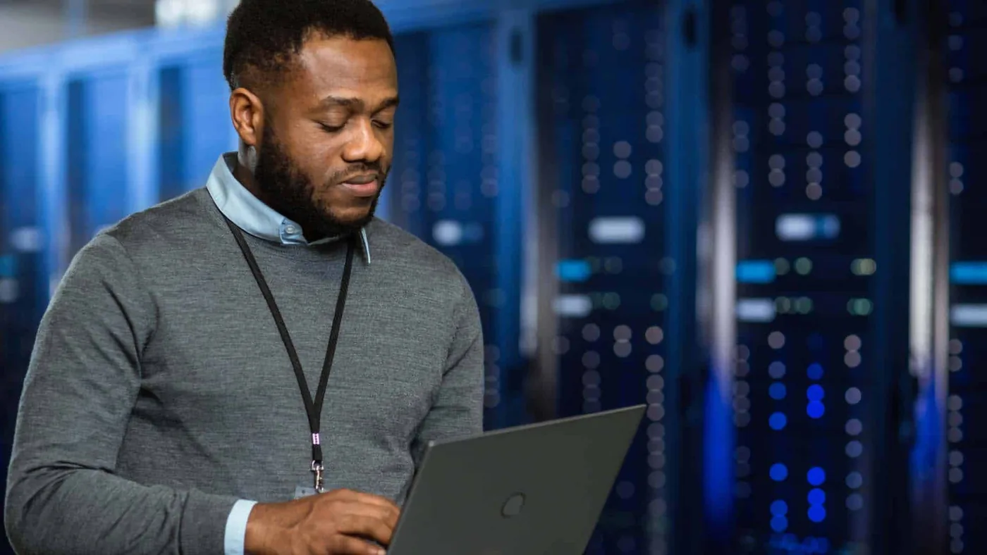 An engineer reviewing systems on a laptop in a data centre