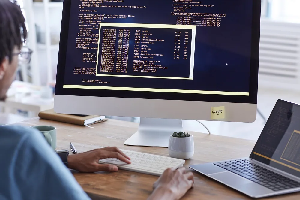 A developer working on code across two screens